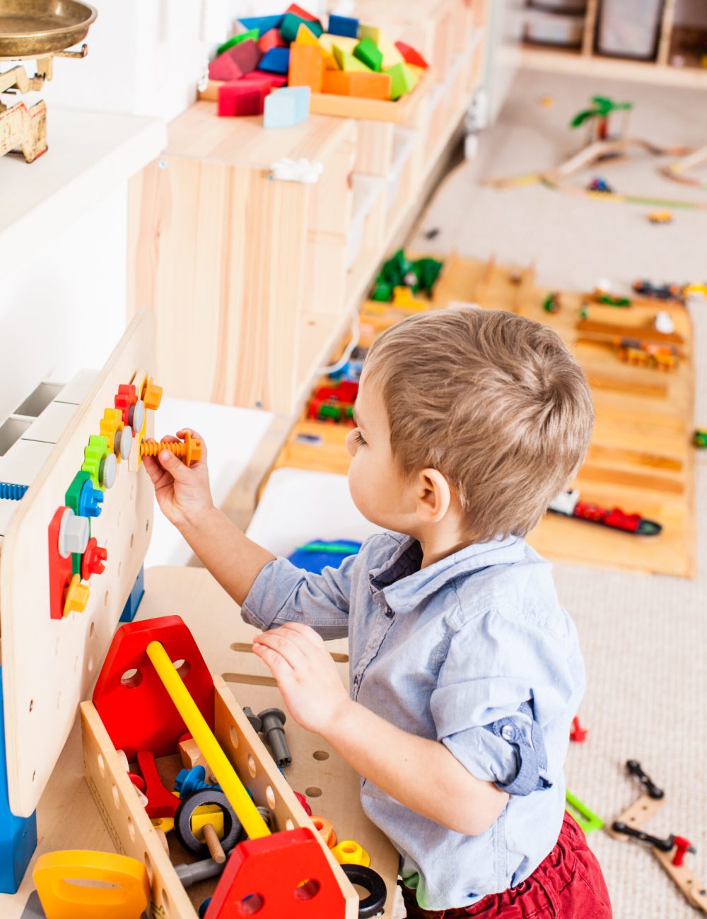 Boy plays with builder wooden instruments in the kindergarten