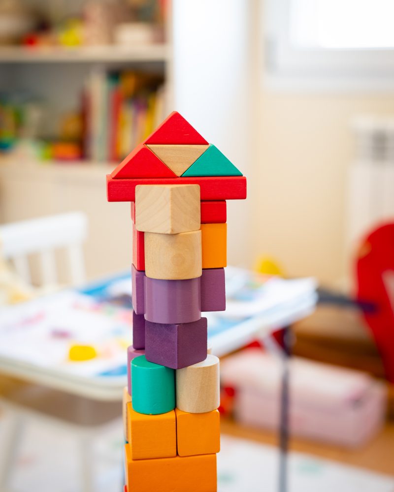 Bright colorful wooden blocks toy. Bricks building tower, castle, children's room as a background